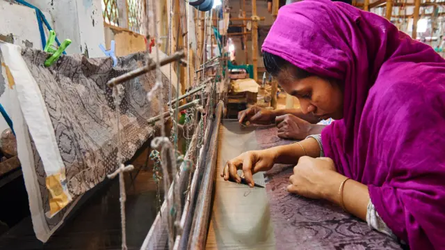 একটি তাঁতে কাজ করছেন একজন নারী