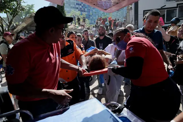 Rescatistas cargan a una mujer en una camilla y la trasladan a una ambulancia en Cali, durante el terremoto.