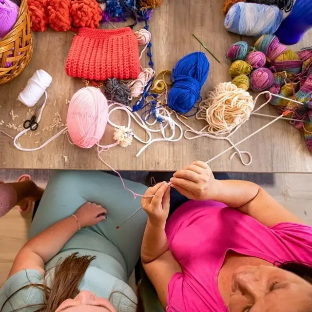 Жінки плетуть, на столі лежить пряжа