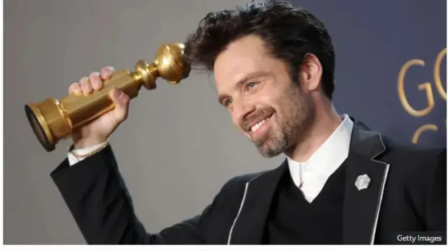 Sebastian Stan fi ami ẹyẹ rẹ han pẹlu ẹrin ayọ.