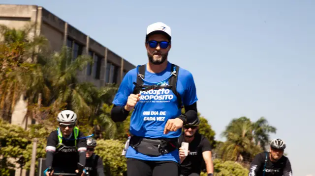 Hugo Farias lo wọ aṣọ alawọ aro, ti awọn oniukẹkẹ mẹta wa lẹyin rẹ.