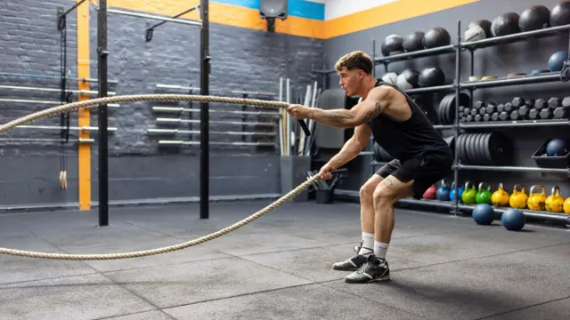 Mężczyzna ćwiczy w linami na siłowni