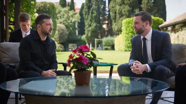 Volodymyr Zelensky e JD Vance sentados, cada um em uma poltrona, conversando. 