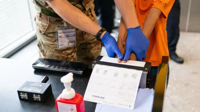 نیروی مرزی بریتانیا در حال انگشت‌نگاری یک پناهجو