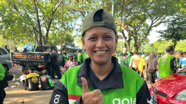 Seorang pengemudi ojol mengacungkan jempol.