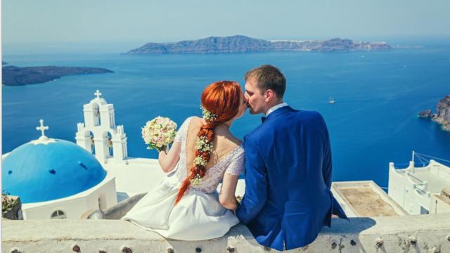 Wedding couple sitting and watching the sea next to a church