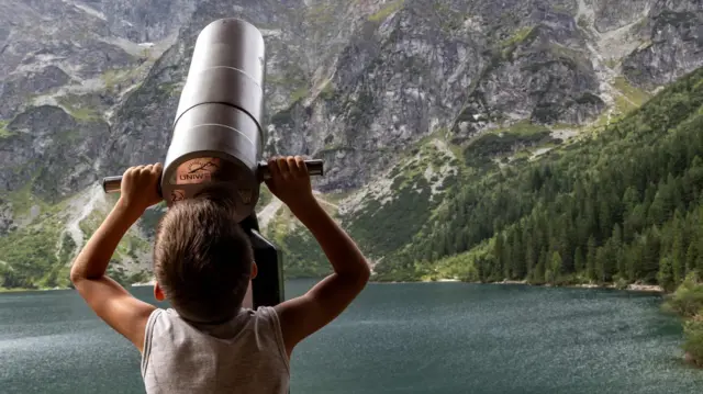 Chłopiec przez teleskop obserwuje zbocza gór wokół Morskiego Oka w Tatrzańskim Parku Narodowym 