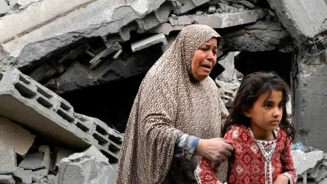 Gazze'de yıkıntılar arasında kız çocuğunu korumaya çalışan bir kadın