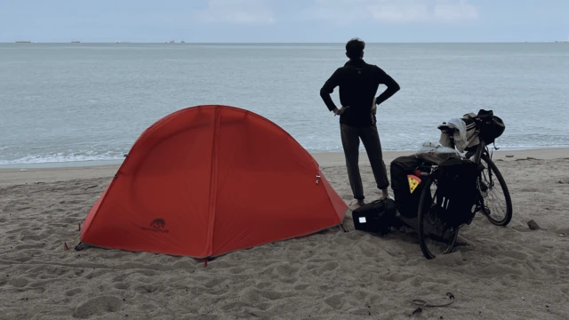 Ari Yami mendirikan tanda dekat sepedanya saat ia berada di pinggir pantai.