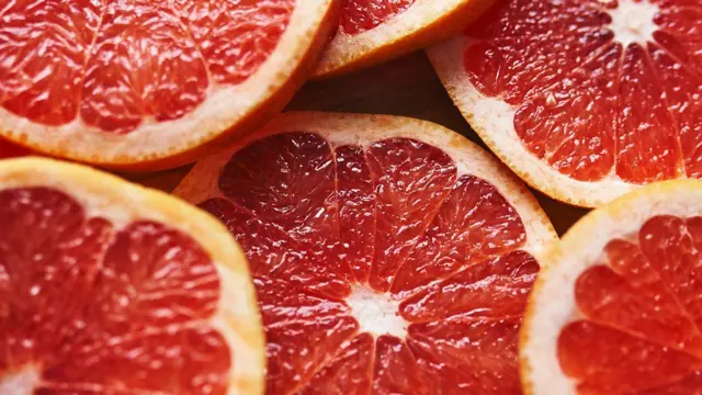شرائح من الجريب فروت لونها أحمر والقشرة برتقالية اللون.