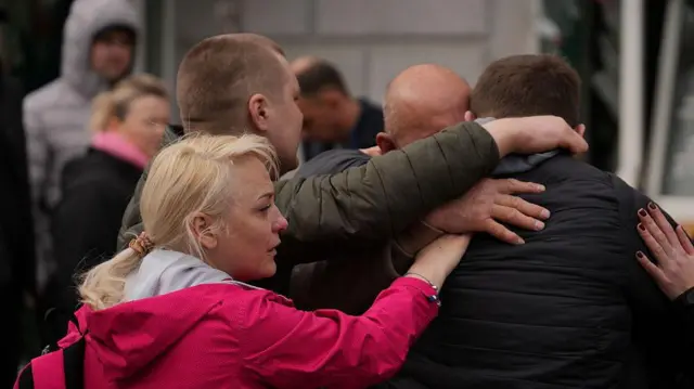People embrace and cry at the site of Russian ballistic strike on April 13, 2025 in Sumy, Ukraine