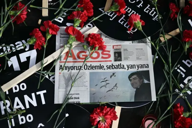 Agos gazetesi, etrafında karanfiller ve Hrant Dink yazan siyah dövizler var. 