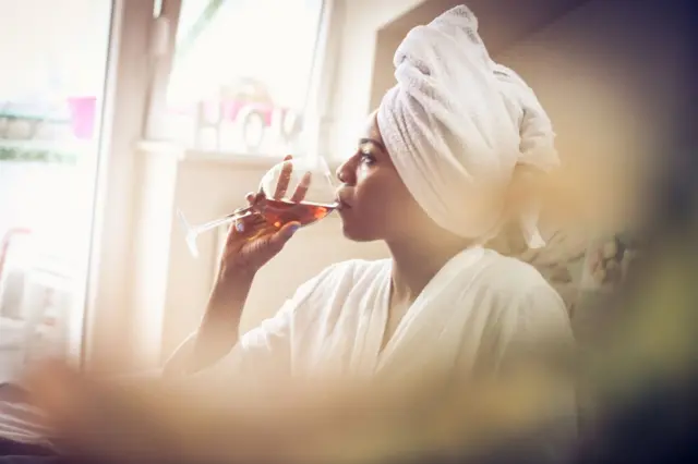 زنی در حال نوشیدن شراب در رختخواب