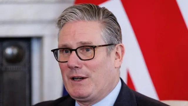 ダークスーツ姿のスターマー氏のアップ写真。メガネをかけ、軽く口を開いている