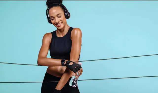 Umukobwa ufise icupa, na ecouteurs mu mutwe, yambaye impuzu zisa n'umukara