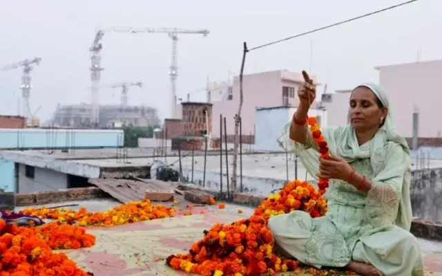 শাকিলা বানু - গাঁদা ফুলের মালা গাঁথছেন। মন্দির অর্থনীতিতে হিন্দু - মুসলমান উভই জড়িয়ে আছেন