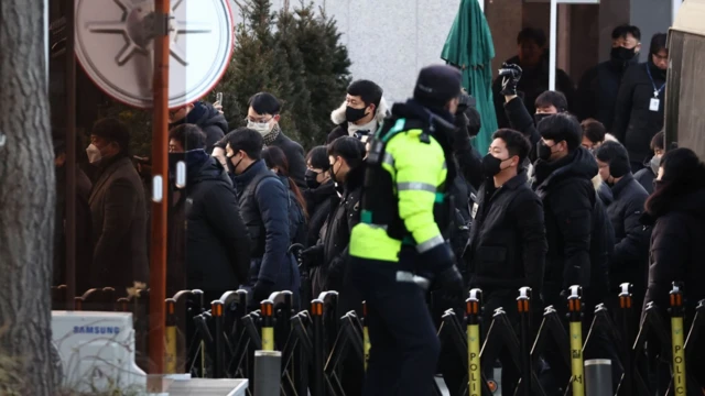 Penyelidik dari badan antikorupsi Korsel berjalan ke pintu masuk kediaman resmi Presiden Yoon Suk Yeol yang dimakzulkan untuk melaksanakan surat perintah penahanan Yoon di Seoul, Korea Selatan, pada 3 Januari 2025.