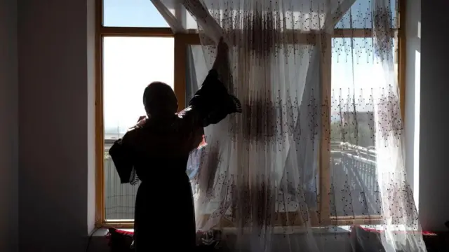 دختر افغان پشت پنجره ایستاده است 