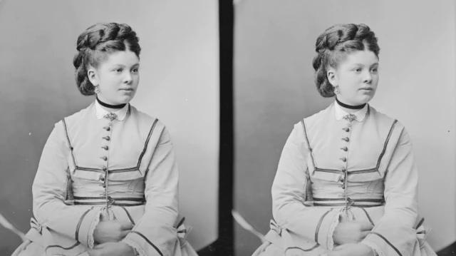Retrato de una joven Sofía. Está sentada frente a la cámara y aparta la mirada. Lleva un vestido claro y el pelo recogido.