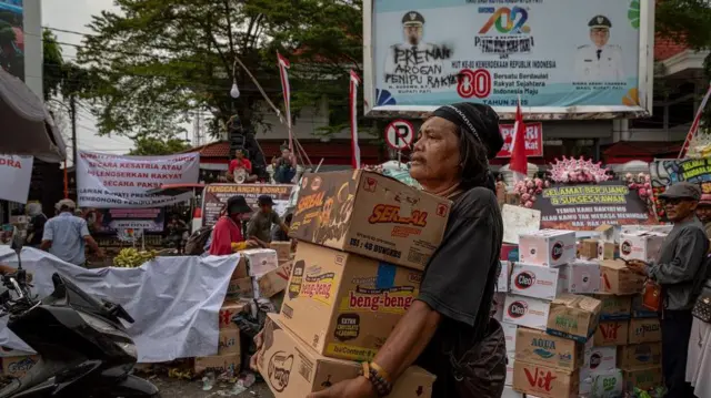 Seorang warga membawa makanan ringan untuk didonasikan ke posko penggalangan donasi logistik unjuk rasa di depan Kantor Bupati Pati, Kabupaten Pati, Jawa Tengah, Selasa (12/8/2025).