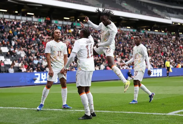 Martial Godo célèbre le troisième but de son équipe avec ses coéquipiers Guela Doué et Evann Guessand lors d'un match amical international entre la Corée du Sud et la Côte d'Ivoire, le 28 mars 2026 à Milton Keynes, en Angleterre.