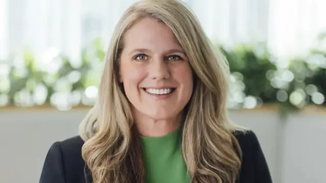 تريسي فرانكلين تبتسم وهي ترتدي سترة داكنة وقميصاً أخضر