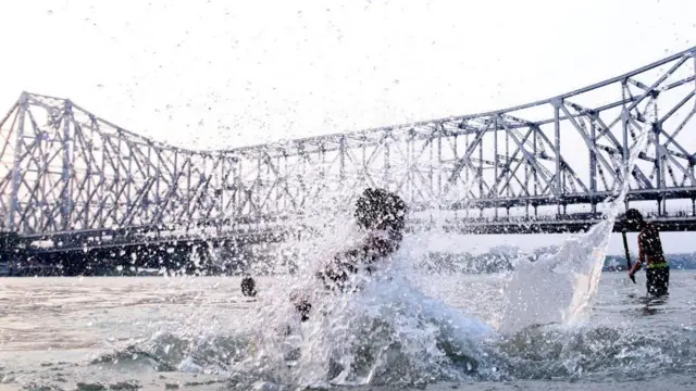 তীব্র তাপপ্রবাহের মধ্যে বৃষ্টির দেখা নেই, তাই হাওড়া ব্রিজের পাশে গঙ্গায় দাপাদাপি শিশুদের