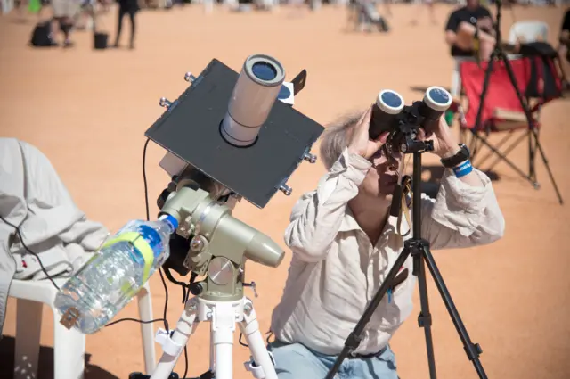 Observador usa binóculo para acompanhar eclipse