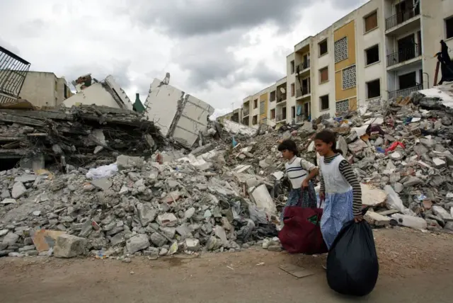 فتاتان تحملان إمدادات بالقرب من بناية مهدمة في أعقابل زلزال بومدراس عام 2003