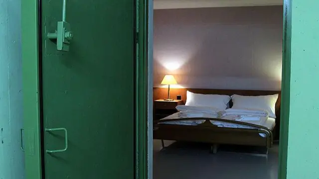 Um quarto de hotel dentro de um bunker com uma porta verde