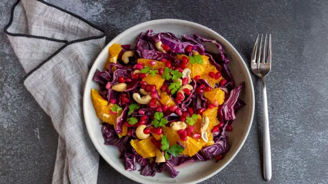 Салат з червоної капусти з червоним апельсином, горіхами кеш'ю та зернами граната - стокова фотографія