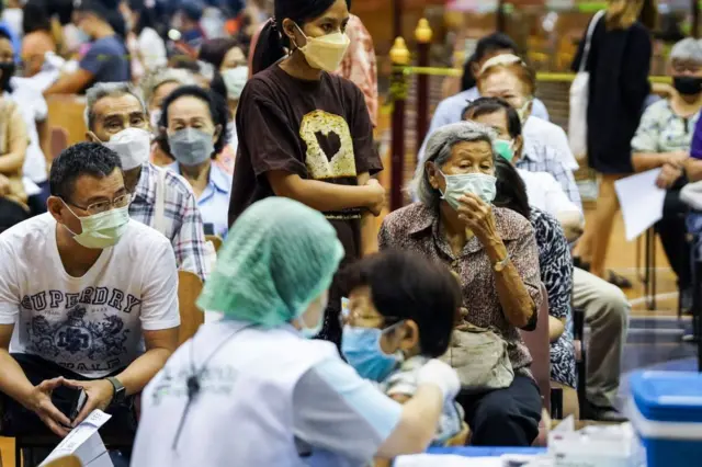 People sit and wait up to receive the COVID-19 vaccine booster vaccine at a vaccination center inside a stadium in Bangkok, Thailand, 03 December 2022. 
