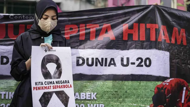 Anggota komunitas CentennialZ memegang poster saat melakukan "Aksi Duka 1 Juta Pita Hitam" di kawasan Senayan, Jakarta, Jumat (31/03)