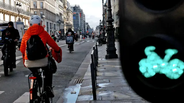 Kolarka w pomarańczowej kurtce jedzie ścieżką rowerową w Paryżu