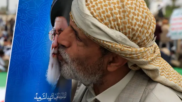 Участник хуситского митинга целует портрет покойного верховного лидера Ирана аятоллы Али Хаменеи