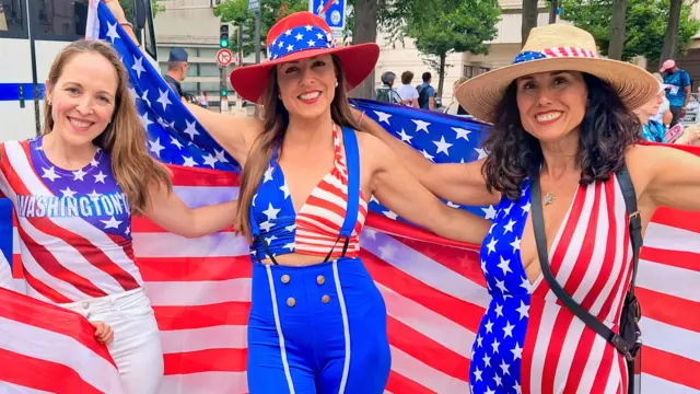 Marisa e outras duas mulheres, vestidas com trajes americanos, posam para uma foto