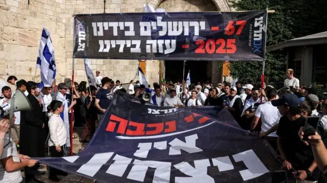 羽生頼語で「67年にエルサレムは我々の手に、2025年にガザは我々の手に」と書かれた大きな横断幕を大勢の人々が掲げている