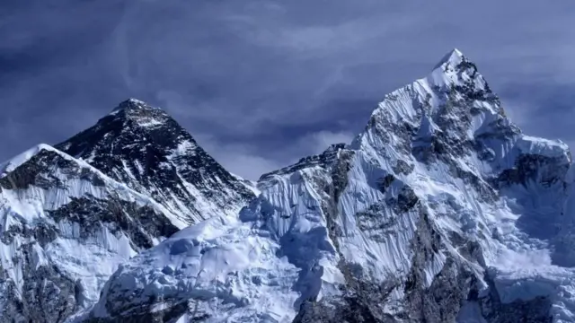 Monte Everest. Dois picos nevados. O céu está azul escuro e parece tempestuoso.