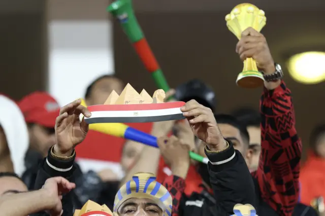 مشجعان لمنتخب مصر يحمل أحدهما كأس البطولة الأفريقية وآخر علم مصر وفوقه أهرامات 