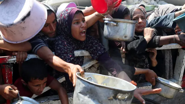 فلسطينيون ينتظرون الحصول على الطعام من مطبخ خيري في مدينة غزة
