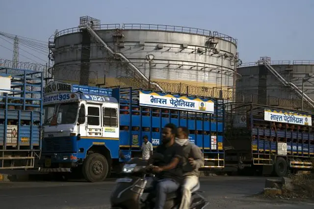 Два чоловіки на мотоциклі на тлі НПЗ в Індії