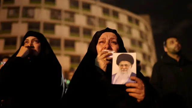 Uma mulher chorando e segurando a foto de Ali Khamenei