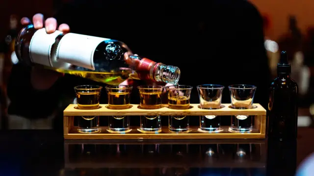 Pessoa servindo shots de bebida alcoólica destilada