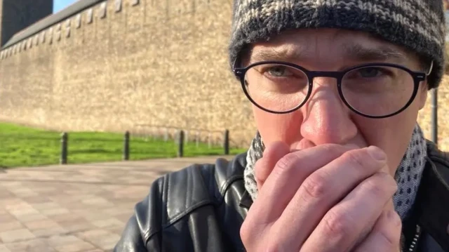 مردی در حال گرم کردن دستانش با بازدم دهان