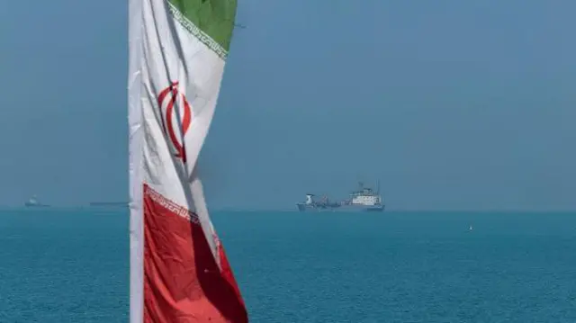 Buşehr'den çekilen fotoğrafta İran bayrağı ve Basra Körfezi'nde seyreden bir tanker görülüyor.