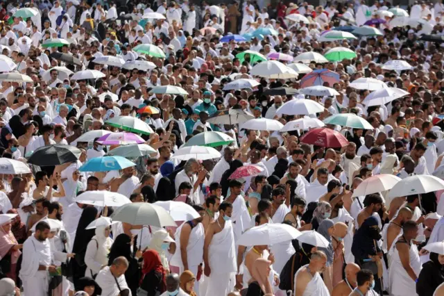 ጃንጥላ የያዙ እና ነጭ የለበሱ በርካታ የእስልምና እምነት ተከታዮች በመካ 