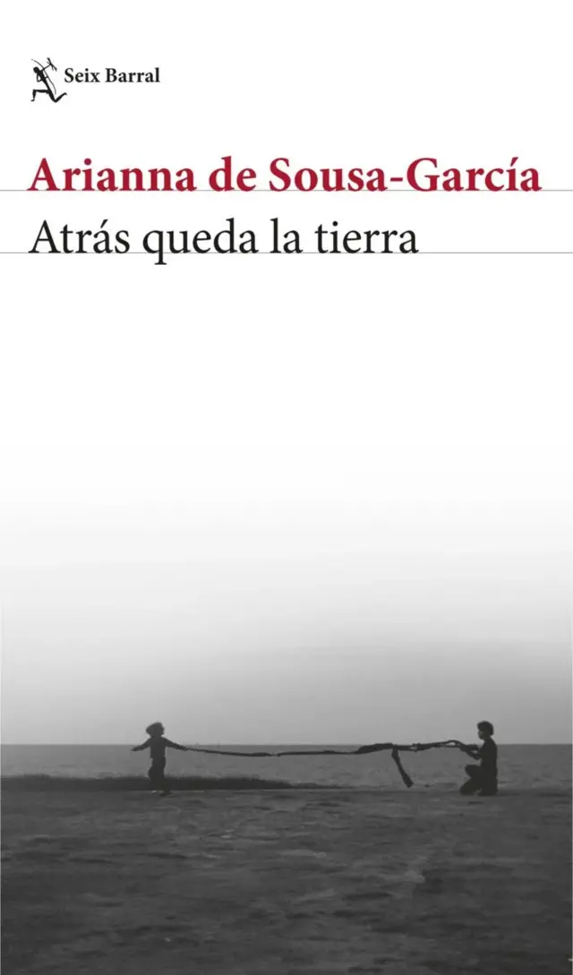 Portada del libro “Atrás queda la tierra” de Arianna de Sousa‑García, sobre una fotografía en blanco y negro de dos personas sosteniendo una larga tela frente a un paisaje abierto.
