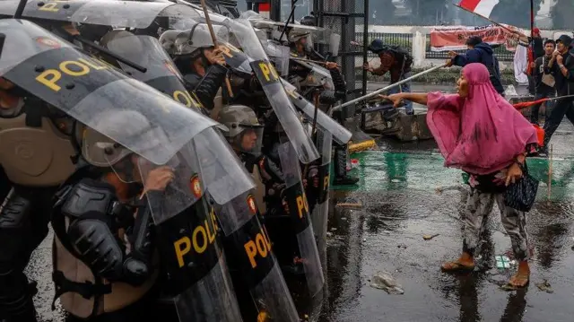 Seorang perempuan menghadapi barisan polisi dalam demonstrasi di depan Gedung DPR, pada Kamis (28/08).