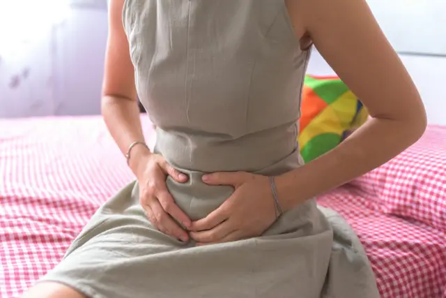 Karnını tutan genç bir kadın