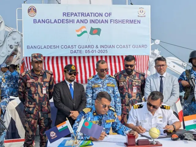 জেলে বিনিময়ের সময় দুই দেশের কোস্টগার্ড কর্মকর্তারা কাগজপত্রে স্বাক্ষর করছেন